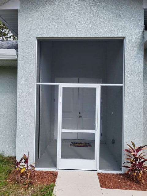 White framed glass door and window with screen on light gray building exterior