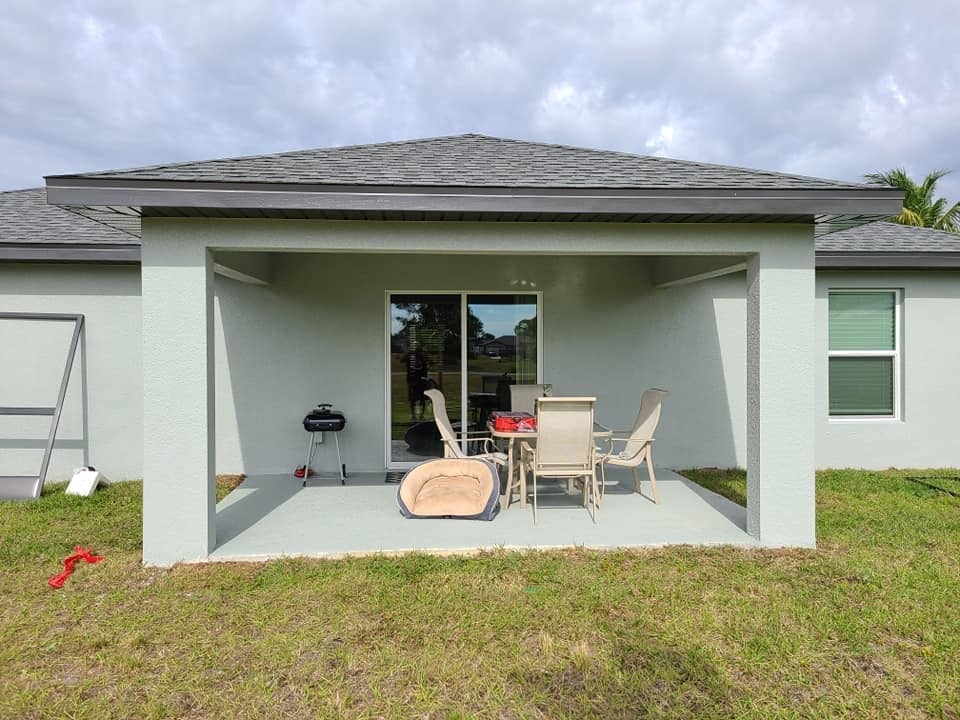 Modern single-story house with covered patio area containing outdoor furniture and grill