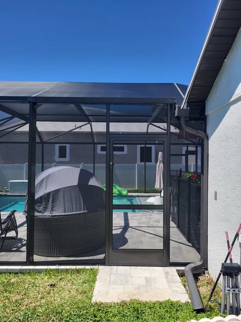 Modern poolside patio with black aluminum pergola and screen enclosure